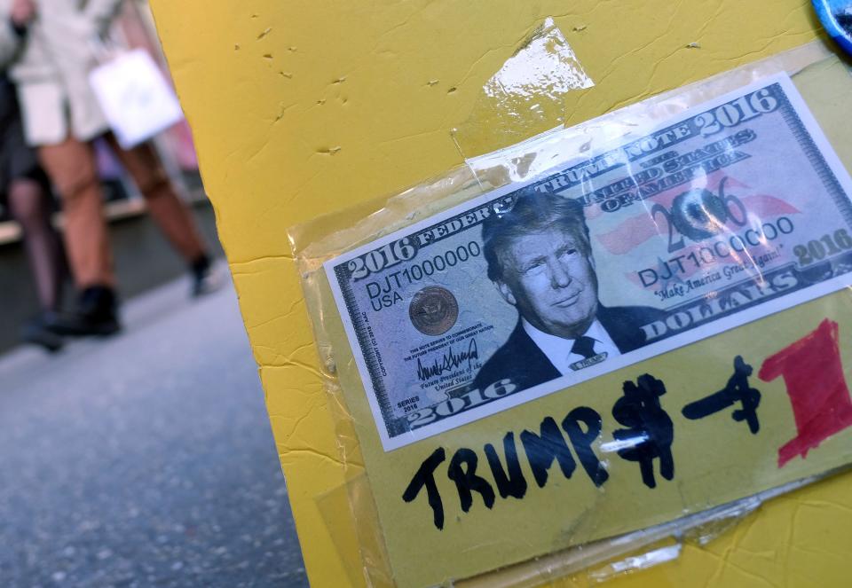 A fake dollar bill with US Republican presidential candidate Donald Trump's picture on it is displayed for sale with other electoral items at a roadside stall as pedestrians walk past in New York on February 26, 2016. White House hopefuls Ted Cruz and Marco Rubio unleashed a barrage of attacks against Donald Trump during raucous Republican debate on February 25, as they sought to halt the billionaire frontrunner's seemingly relentless march to the party's nomination. / AFP / Jewel Samad        (Photo credit should read JEWEL SAMAD/AFP/Getty Images)