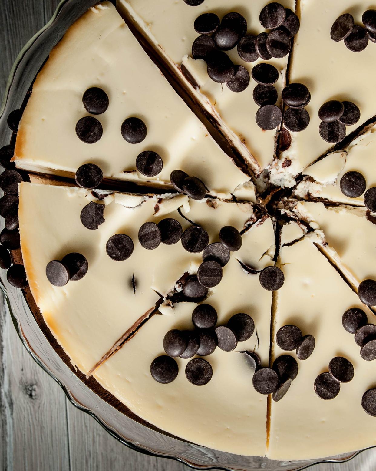 Top view of chocolate chip cheesecake in a glass pie dish with a grey wooden table background