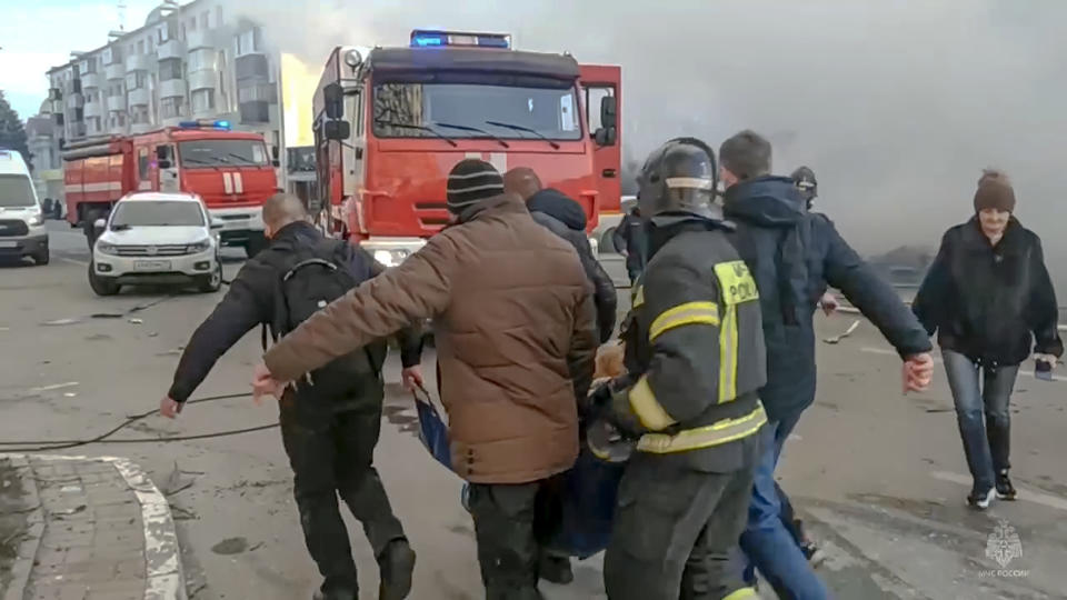 In this photo taken from video released by Russia Emergency Situations Ministry telegram channel on Saturday, Dec. 30, 2023, Rescuers and people carry a wounded person after shelling in Belgorod, Russia. Russian officials have accused Ukrainian forces of shelling the Russian border city of Belgorod. Two children were killed in Saturday's attack, regional governor Vyacheslav Gladkov said in a statement on social media. He also said that an unspecified number of people had been injured. (Russia Emergency Situations Ministry telegram channel via AP)