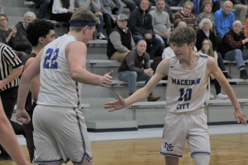 Mackinaw City juniors Lucas Bergstrom (22) and Sabastian Pierce (10) celebrate after Bergstrom scored a basket and was fouled during the third quarter against Harbor Light at home on Tuesday.