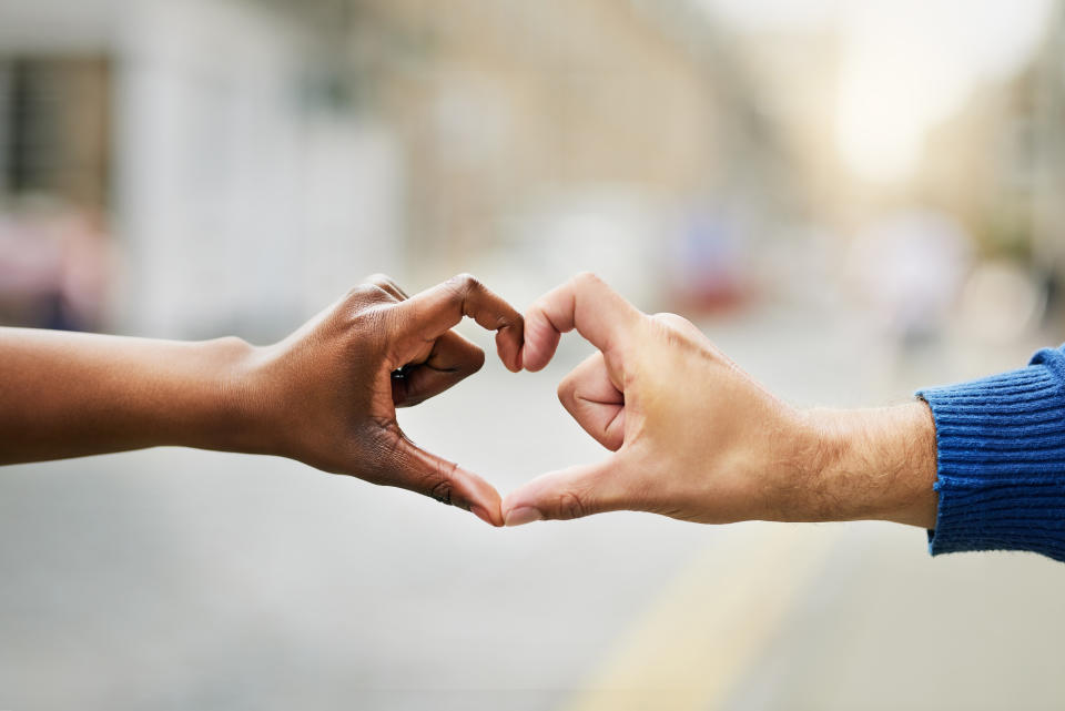 Closeup shot of an unrecognizable couple making a heart shape with their hands outside