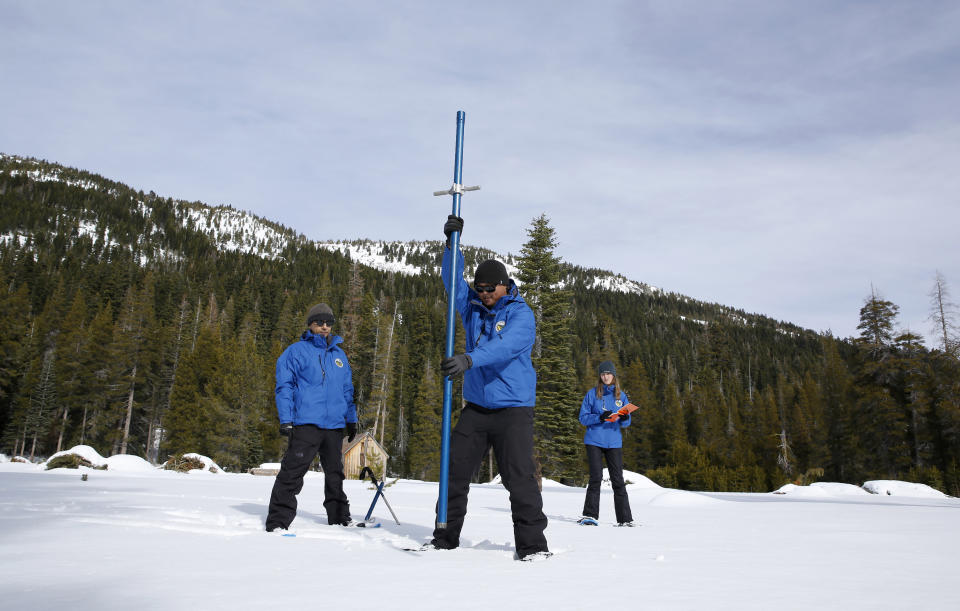 Sean de Guzman, center, chief of snow surveys for the California Department of Water Resources, plunges a snow survey tube into the snowpack during the first snow survey of the season at Phillips Station near Echo Summit, Calif., Thursday, Jan. 2, 2020. The survey found the snowpack at 33.5 inches deep with a water content of 11 inches which is 97% of average at this location at this time of year. Also seen are DWR's Ramesh Gautam, left, and Lauren Miller. (AP Photo/Rich Pedroncelli)