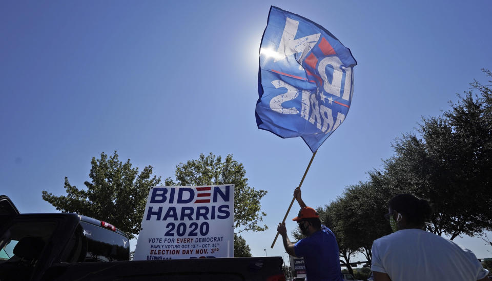 A supporter of Democratic presidential candidate former Vice President Joe Biden places a flag on a pick-up truck bed in for a Ridin' With Biden event Sunday, Oct. 11, 2020, in Plano, Texas. Democrats in Texas are pressing Joe Biden to make a harder run at Texas with less than three weeks until Election Day. (AP Photo/LM Otero)
