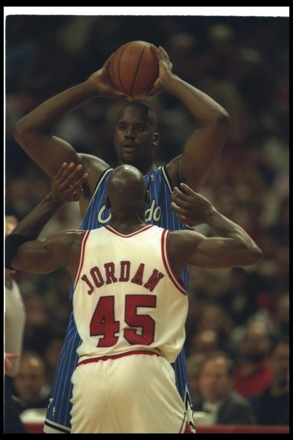 Center Shaquille O'Neal looks to pass the ball as Chicago Bulls guard Michael Jordan covers him during a game at the United Center in Chicago, Illinois on March 24, 1995. (Allsport)