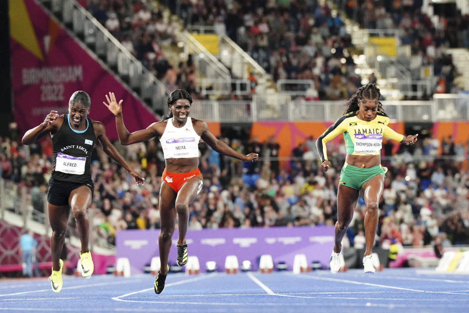 Jamaica's Elaine Thompson-Herah, right, races to win gold in the women's 100m final during the athletics in the Alexander Stadium at the Commonwealth Games in Birmingham, England, Wednesday, Aug. 3, 2022. At left is Saint Lucia's Julien Alfred, who finished second and England's Daryll Neita, second left who finished third. (Mike Egerton/PA via AP)