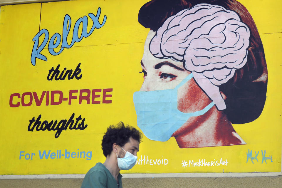 FILE - In this May 23, 2020, file photo, a man wears a face mask while walking under a sign that reads "Relax think COVID free thoughts" during the coronavirus outbreak in San Francisco. (AP Photo/Jeff Chiu, File)