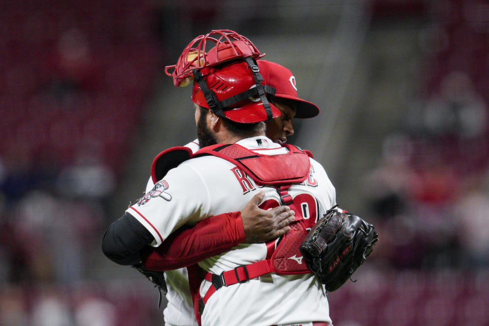 Cincinnati Reds relief pitcher Alexis Diaz, center left, embraces catcher Austin Romine (28) after their baseball game against the Chicago Cubs, Monday, Oct. 3, 2022, in Cincinnati. (AP Photo/Jeff Dean)