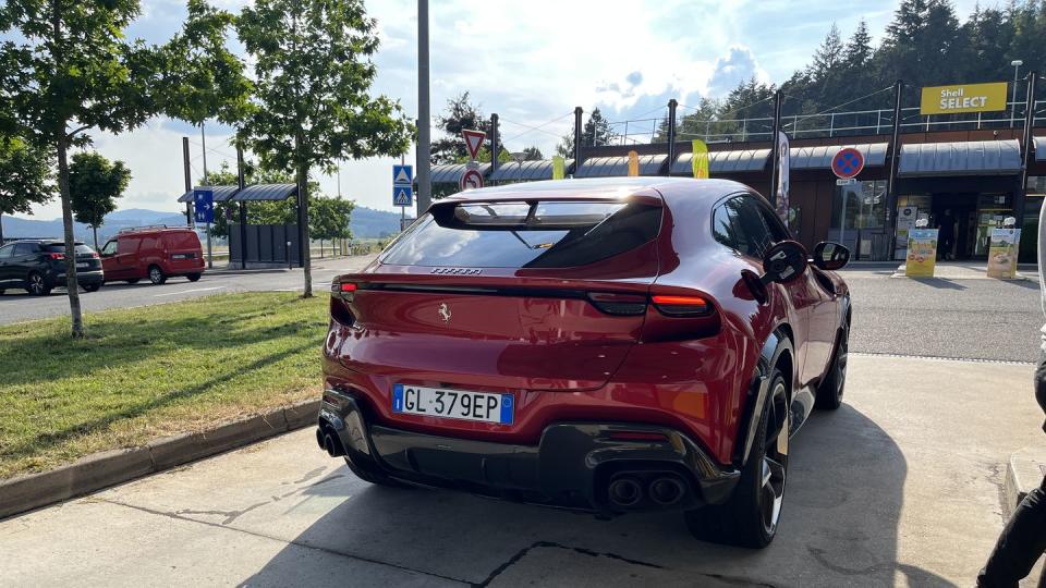 a red ferrari purosangue parked on grass