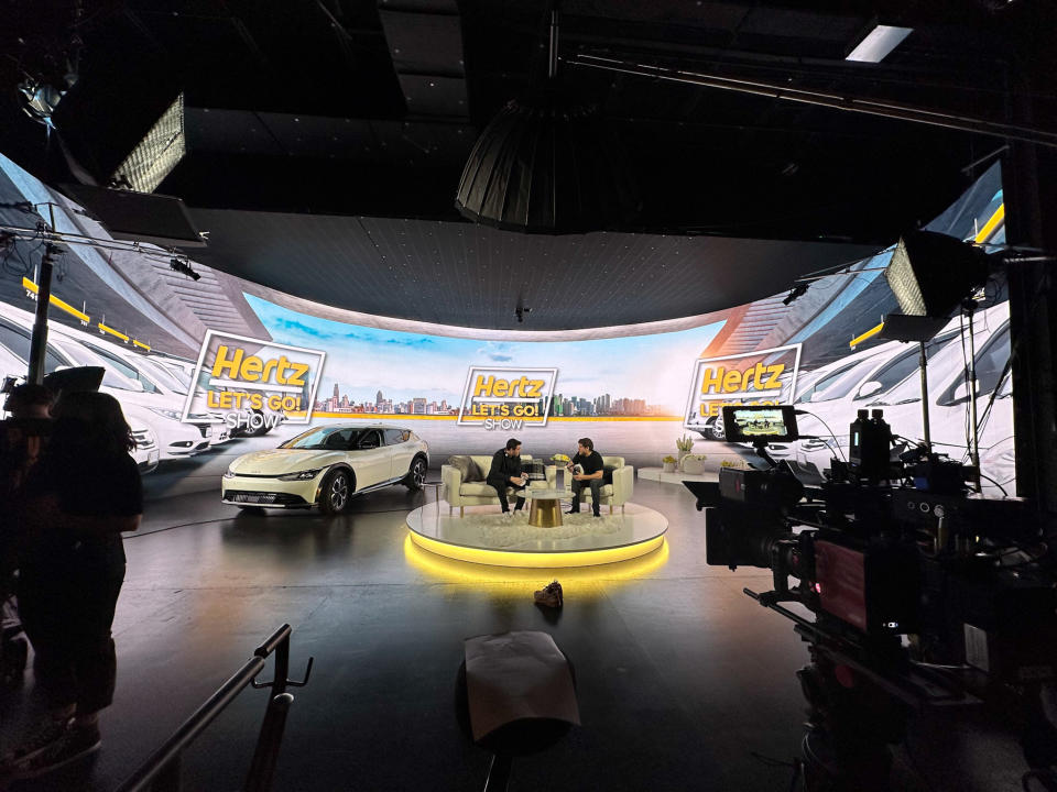 Behind the scenes view of a Hertz commercial shoot showing cameras, lights and a set.