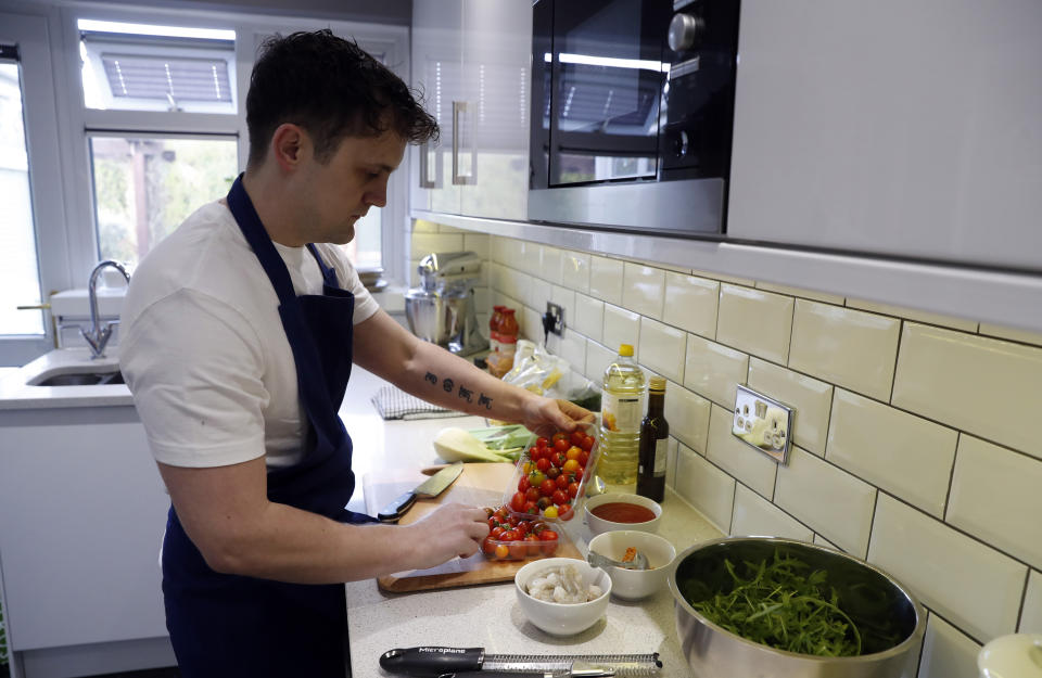 Jon Watts, demonstrates his cooking skills for the Associated Press by making a prawn linguini at a friends kitchen in Codicote, Welwyn, England, Thursday, April 15, 2021. Jon Watts was 18 years old when he woke up in a prison cell and decided he had to change. He enrolled in every course he could find, from mathematics to business. But he says it was a program founded by Prince Philip, the Duke of Edinburgh, that gave him a “passion for food” and a career as a chef when he got out of prison 3 1/2 years later. (AP Photo/Alastair Grant)