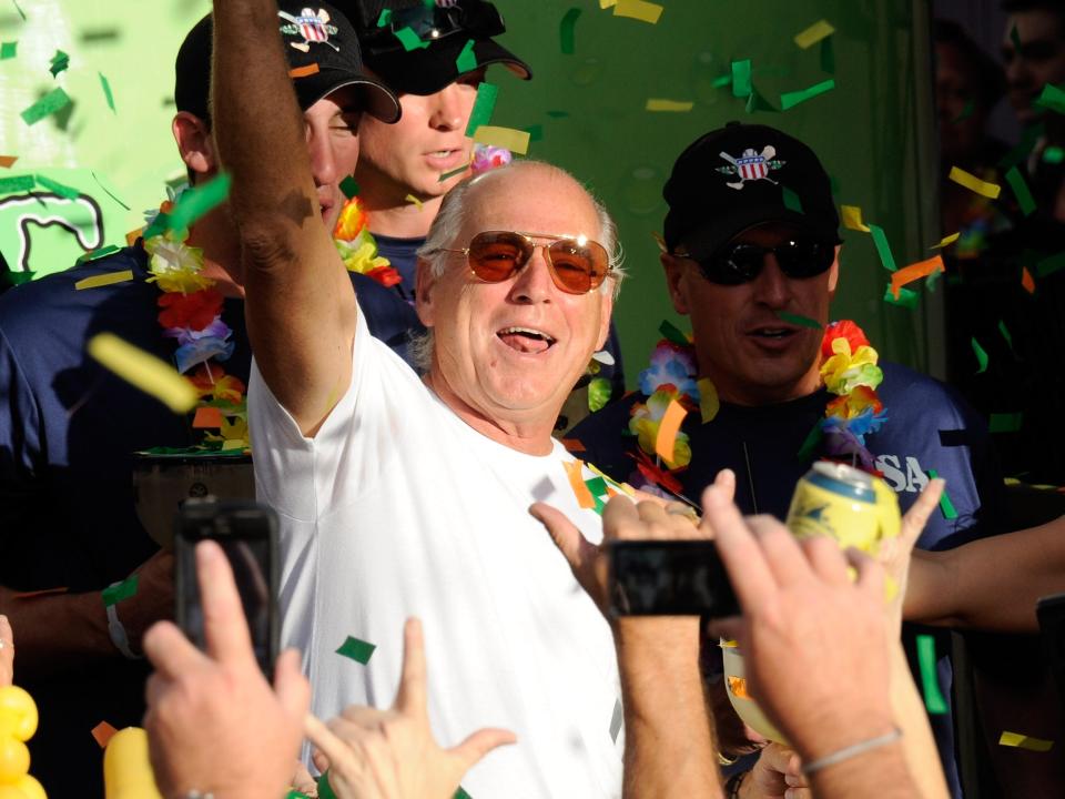 Recording artist Jimmy Buffett stands with members of the Wounded Warrior Amputee Softball Team as he gestures to the crowd during the grand opening celebration for the Margaritaville Casino at Flamingo Las Vegas October 14, 2011 in Las Vegas, Nevada. The casino set the Guinness World Records title for largest gallon beverage with an 8,500-gallon, two-story Margarita named "Lucky Rita."