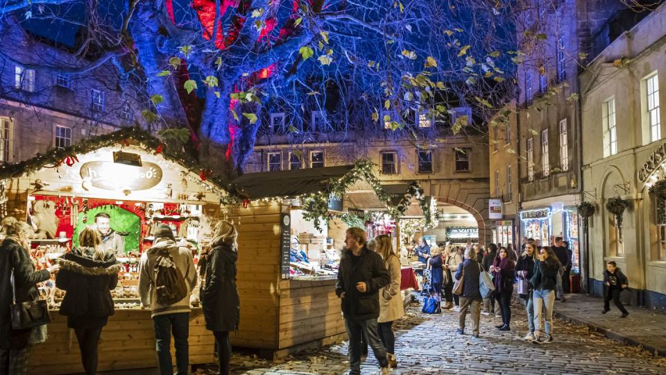 people at the christmas market set up in abbey green, in the old town of bath