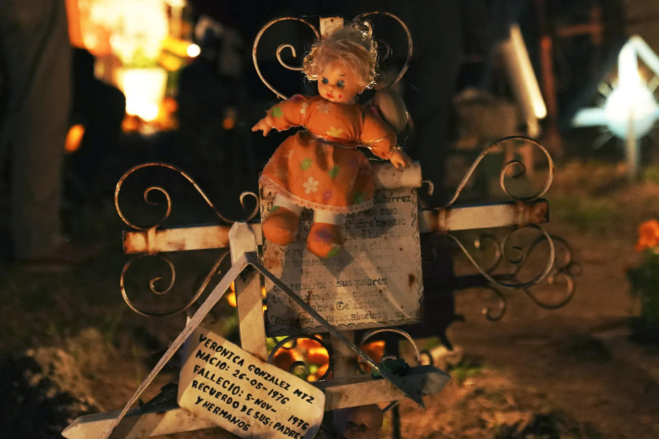 A doll decorates a newborn's tomb at the San Gregorio Atlapulco cemetery during Day of the Dead festivities on the outskirts of Mexico City, Wednesday, early Nov. 1, 2023. In a tradition that coincides with All Saints Day on Nov. 1 and All Souls Day on Nov. 2, families decorate graves with flowers and candles and spend the night in the cemetery, eating and drinking as they keep company with their dearly departed. (AP Photo/Marco Ugarte)