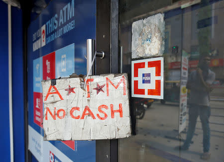 FILE PHOTO: A man is reflected on the door of an automated teller machine (ATM) facility with a sign in Bengaluru, India, April 18, 2018. REUTERS/Abhishek N. Chinnappa/File Photo