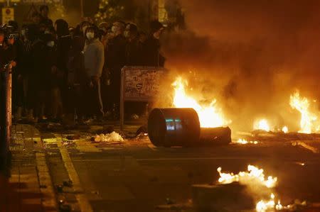 Protesters stand behind a fire set by them at a junction at Mongkok district in Hong Kong, China February 9, 2016. REUTERS/Bobby Yip