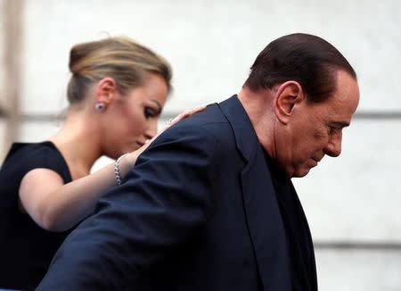 Former Italian Prime Minister Silvio Berlusconi leaves the stage flanked by his girlfriend Francesca Pascale at the end of a rally to protest his tax fraud conviction, outside his palace in central Rome, Italy August 4, 2013. REUTERS/Alessandro Bianchi/