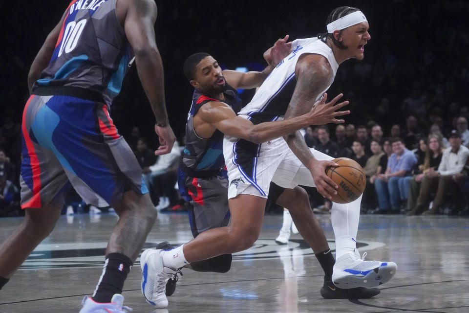 Brooklyn Nets' Mikal Bridges, center, attempts to strip ball from Orlando Magic's Paolo Banchero, right, during the first period of an NBA basketball game, Saturday, Dec. 2, 2023, in New York. (AP Photo/Bebeto Matthews)