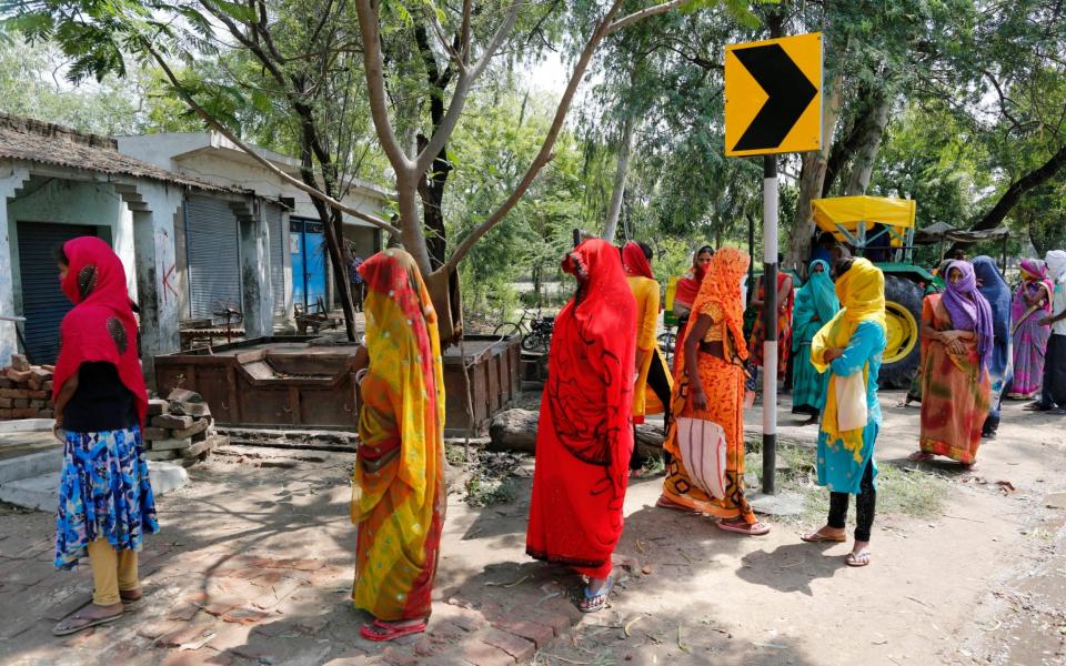 Indian women queue for relief money - Rajesh Kumar Singh/AP