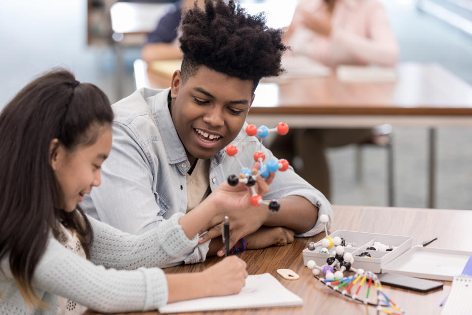 A older student helping a younger one with a science project