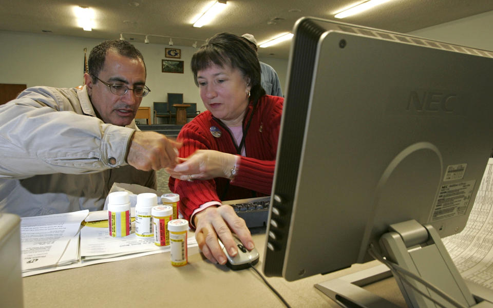 PLEASANTON, CA - DECEMBER 19:  Volunteer Rebecca Cox (R) helps a man log perscription drug information as he registers his parents for the new Medicare drug prescription program during a Medicare enrollment event December 19, 2005 in Pleasanton, California. Open enrollment for the new program began November 15 and will continue through May 15, 2006.  (Photo by Justin Sullivan/Getty Images)