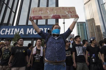 A protester holds up a placard which reads "Peace is our greatest weapon", outside the venue of the official flag-raising ceremony for celebrations of China's National Day, in Hong Kong October 1, 2014. REUTERS/Tyrone Siu