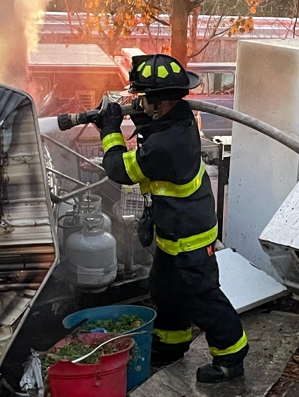 A Knoxville Fire Department firefighter works to extinguish a camper on fire at 3901 Greenway Drive on Thursday morning.