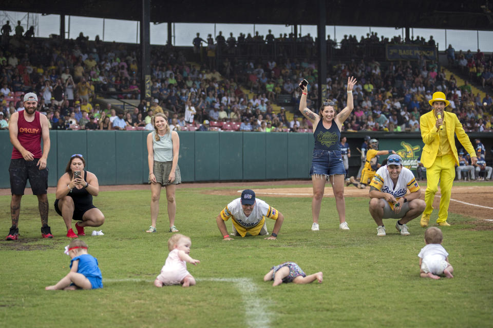 Four infants and their parents take part in what the Savannah Bananas call The Slowest Race, at the team's baseball game against the Wilmington Sharks, Saturday, June 11, 2022, in Savannah, Ga. (AP Photo/Stephen B. Morton)