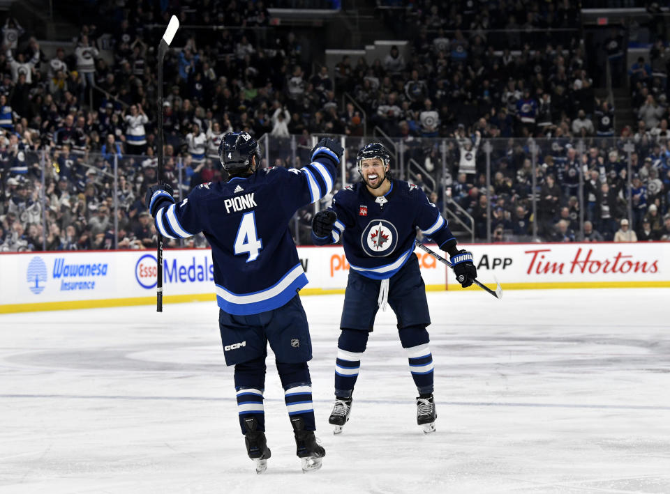 Winnipeg Jets' Neal Poink (4) celebrates his goal against the Tampa Bay Lightning with Brenden Dillon during the second period of an NHL hockey game Tuesday, Jan. 2, 2024, in Winnipeg, Manitoba. (Fred Greenslade/The Canadian Press via AP)