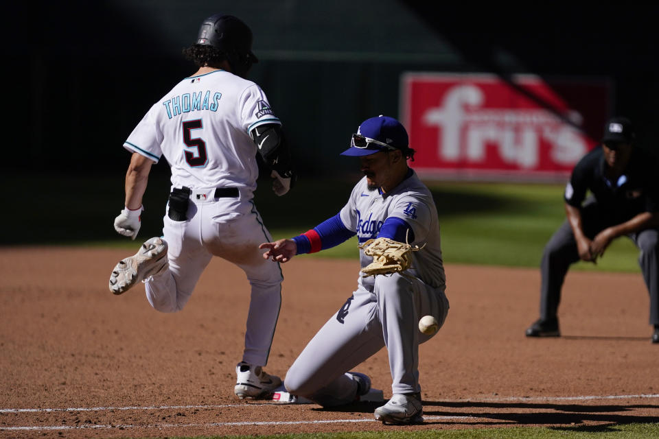 Arizona Diamondbacks' Alek Thomas (5) reaches first base safely as Los Angeles Dodgers first baseman Miguel Vargas, right, is unable to get to the ball after a third swinging strike catch was missed by Dodgers catcher Will Smith during the eighth inning of a baseball game Sunday, April 9, 2023, in Phoenix. The Diamondbacks won 11-6. (AP Photo/Ross D. Franklin)