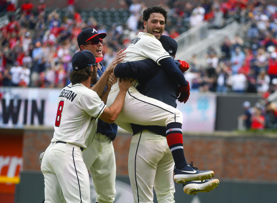 Atlanta Braves' Dansby Swanson is held by teammate Kevin Gausman as they celebrate with Charlie Culberson (8) and Max Fried after Swanson hit a winning RBI-single in the ninth inning to end a baseball game against the Miami Marlins, Sunday, April 7, 2019, in Atlanta. (AP Photo/John Amis)