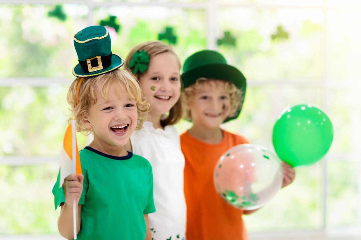 family celebrating st patricks day irish holiday, culture and tradition kids wear green leprechaun hat and beard with ireland flag and clover leaf children having fun at st patrick party