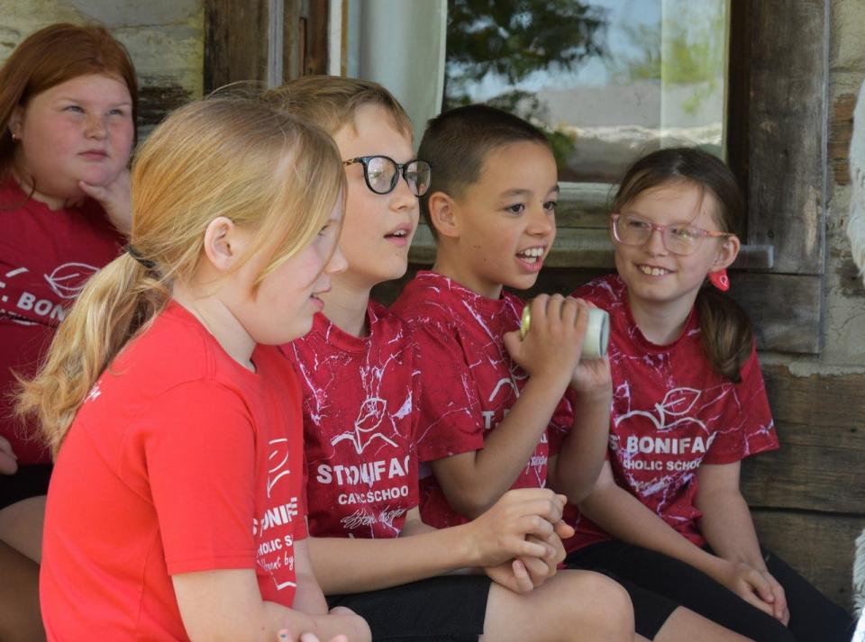 Students from St. Boniface Catholic School “churn” butter by shaking ingredients in a jar.