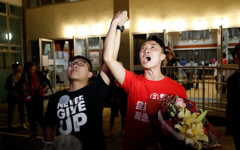 Pro-democracy candidate Jimmy Sham, right, celebrates with a supporter after winning his election in Hong Kong - Credit: VINCENT THIAN/AP PHOTO