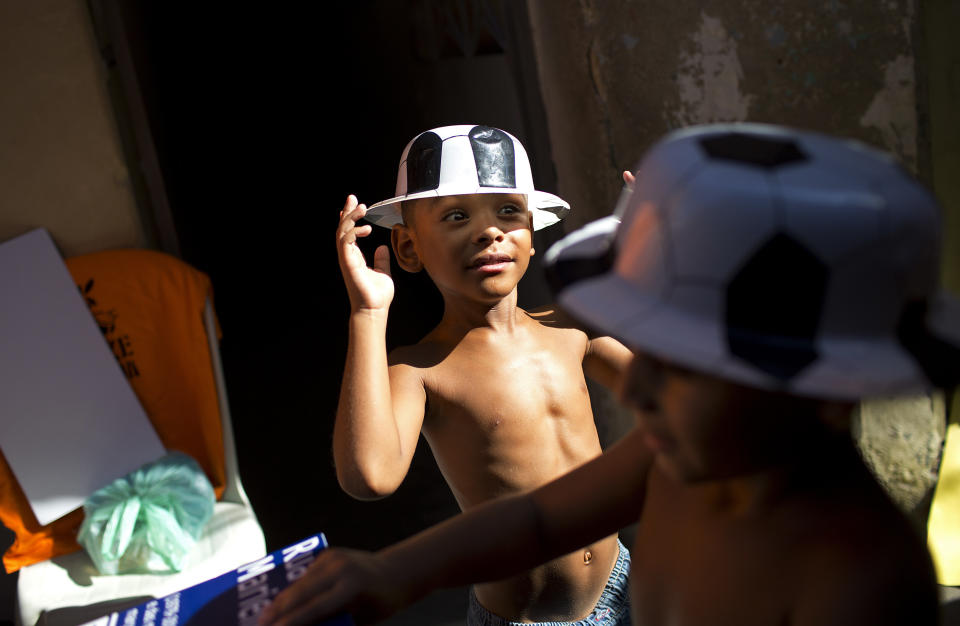 Boys wear carnival costume hats during the "Se Benze que da" block party, created by slain councilwoman Marielle Franco, in the Mare slum of Rio de Janeiro, Brazil, Saturday, Feb. 23, 2019. Merrymakers take to the streets in hundreds of open-air "bloco" parties ahead of Rio's over-the-top Carnival, the highlight of the year for many. (AP Photo/Silvia Izquierdo)
