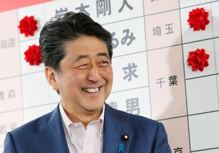 Japan's Prime Minister Shinzo Abe, who is also leader of the ruling Liberal Democratic Party (LDP), reacts as he puts a rosette on the name of a candidate who is expected to win the upper house election, at the LDP headquarters in Tokyo