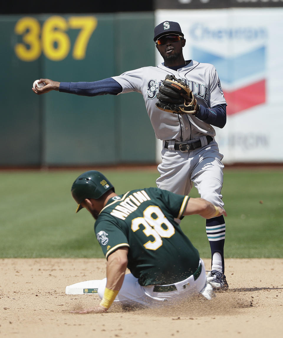 Seattle Mariners' Dee Gordon, top, throws to first base after forcing out Oakland Athletics' Nick Martini (38) on a double play ball hit into by Jed Lowrie during the ninth inning of a baseball game in Oakland, Calif., Wednesday, Aug. 15, 2018. (AP Photo/Jeff Chiu)