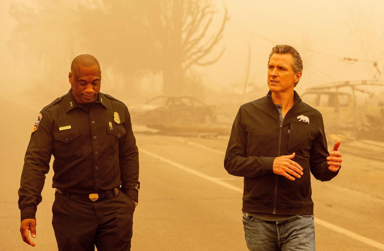 California Governor Gavin Newsom (R) walks with Assistant Region Chief for Cal Fire Curtis Brown (R) in downtown Greenville, Calif. on Aug. 7, 2021.