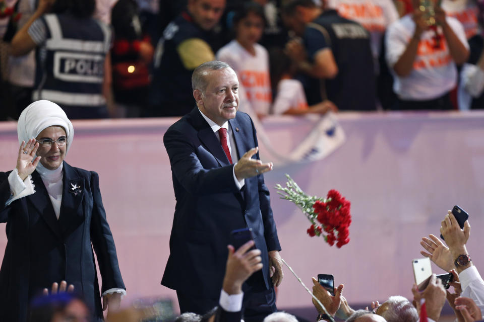 Turkey's President Recep Tayyip Erdogan, accompanied by his wife Emine, left, throws flowers to his supporters as he arrives to deliver a speech at his ruling Justice and Development Party (AKP) congress in Ankara, Turkey, Saturday, Aug. 18, 2018. (AP Photo/Burhan Ozbilici)