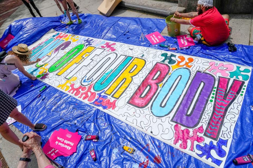 Abortion-rights activists finish a banner in front of the Rhode Island Supreme Court building on South Main Street during Saturday's rally.