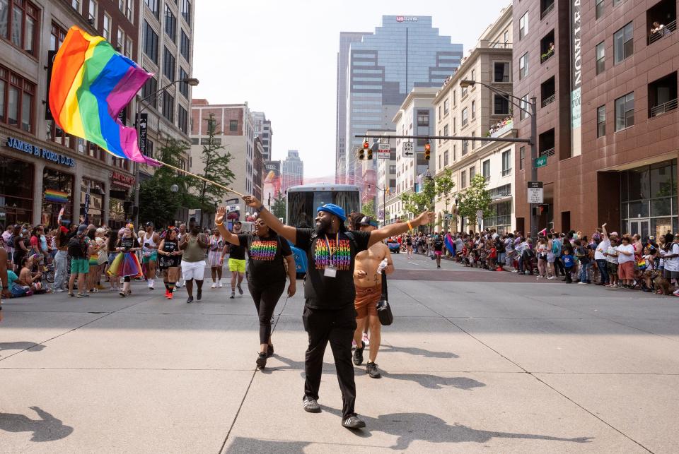 Deairius Houston waves a pride flag while walking with the Central Outreach Wellness Center during the Pride March on Saturday in Downtown Columbus.