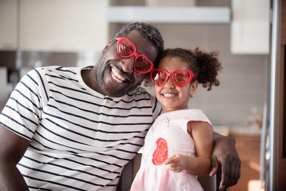 mixed race father and daughter taste lollipop during valentine's day