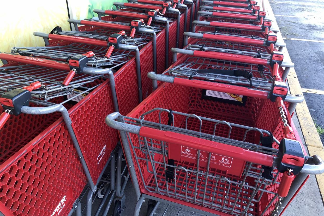 Two rows of red Save A Lot shopping carts outside on sidewalk with a few empty parking spaces