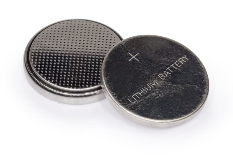 Two lithium button batteries on a white background, close-up in selective focus