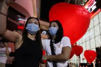 Women wearing protective masks take a selfie in front of hearts celebrating Valentine's Day in front of shopping mall in Bangkok
