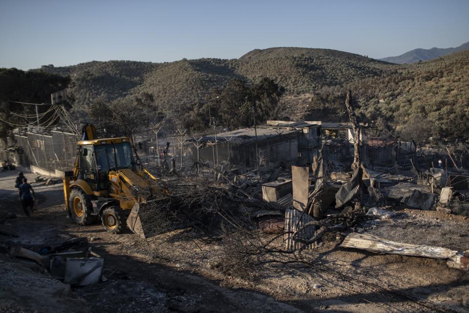 A bulldozer removes the debris from the burned Moria refugee camp on the northeastern island of Lesbos, Greece, Thursday, Sept. 10, 2020. A second fire in Greece's notoriously overcrowded Moria refugee camp destroyed nearly everything that had been spared in the original blaze, Greece's migration ministry said Thursday, leaving thousands more people in need of emergency housing. (AP Photo/Petros Giannakouris)