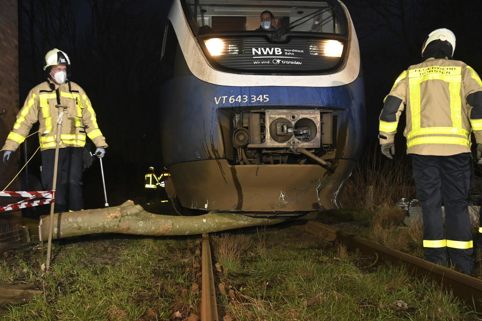 Firefighters clear a tree from a railway track after a storm in Dorsten, Germany, Thursday, Feb. 17, 2022. Deutsche Bahn has suspended long-distance services in several German regions because of the storm. (Bludau Foto/dpa via AP)