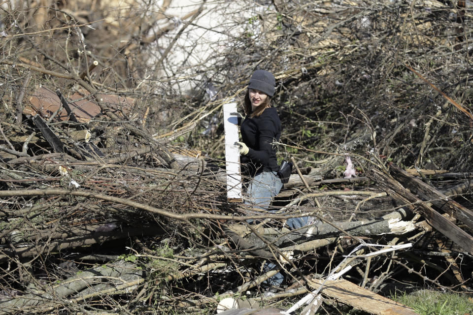 Tiffany Catchim separates construction debris from tree limbs Friday, March 6, 2020, in Nashville, Tenn. Residents and businesses face a huge cleanup effort after tornadoes hit the state Tuesday. (AP Photo/Mark Humphrey)