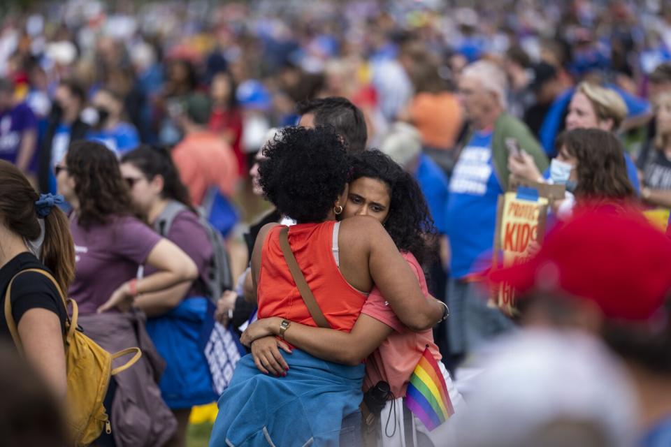 Two women hug in the middle of a crowd