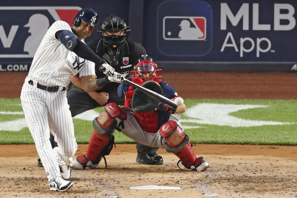 New York Yankees Aaron Hicks, left, connects for a second-inning, RBI double in a baseball game against the Boston Red Sox, Sunday, Aug. 16, 2020, in New York. Red Sox catcher Kevin Plawecki is at right and home plate umpire Ryan Additon is behind the plate.(AP Photo/Kathy Willens)