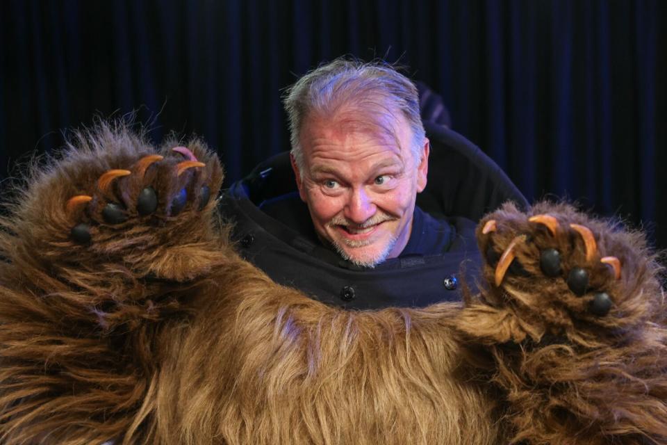 A man in a bear costume reveals his own head.